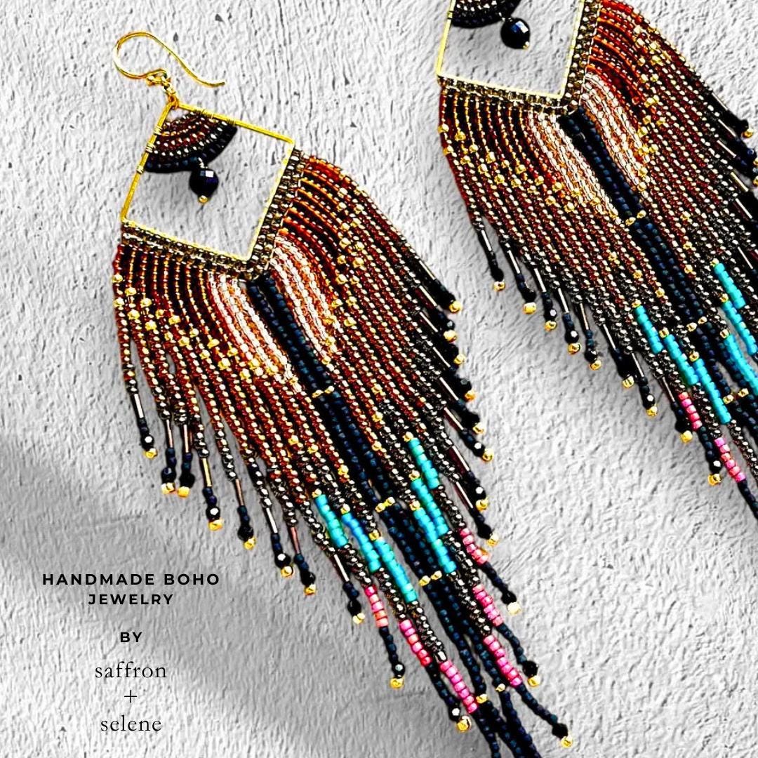 Hand beaded fringe earrings with a feather design hand beaded with seed beads. Black and bronze with highlights of turquoise, pink and metalic gold. Western Glam jewelry for women by Saffron and Selene