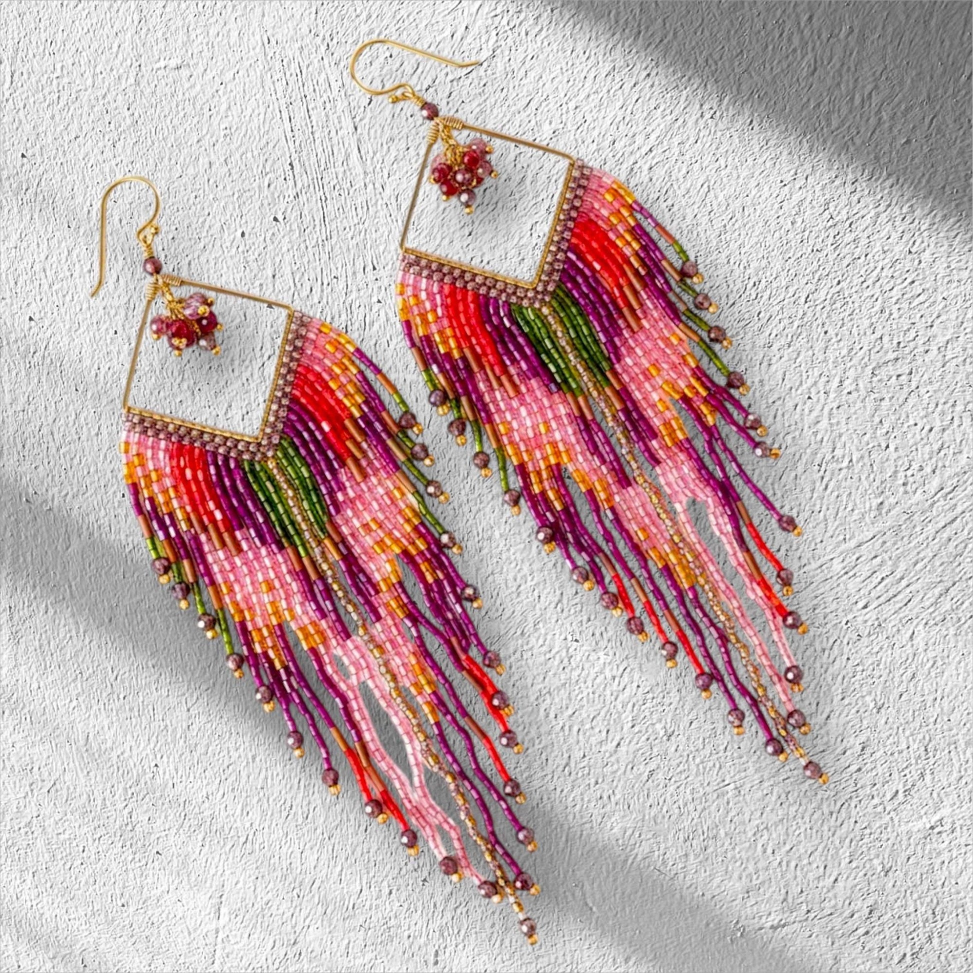 Boho statement earrings in pink magenta orange and gold worn by model
