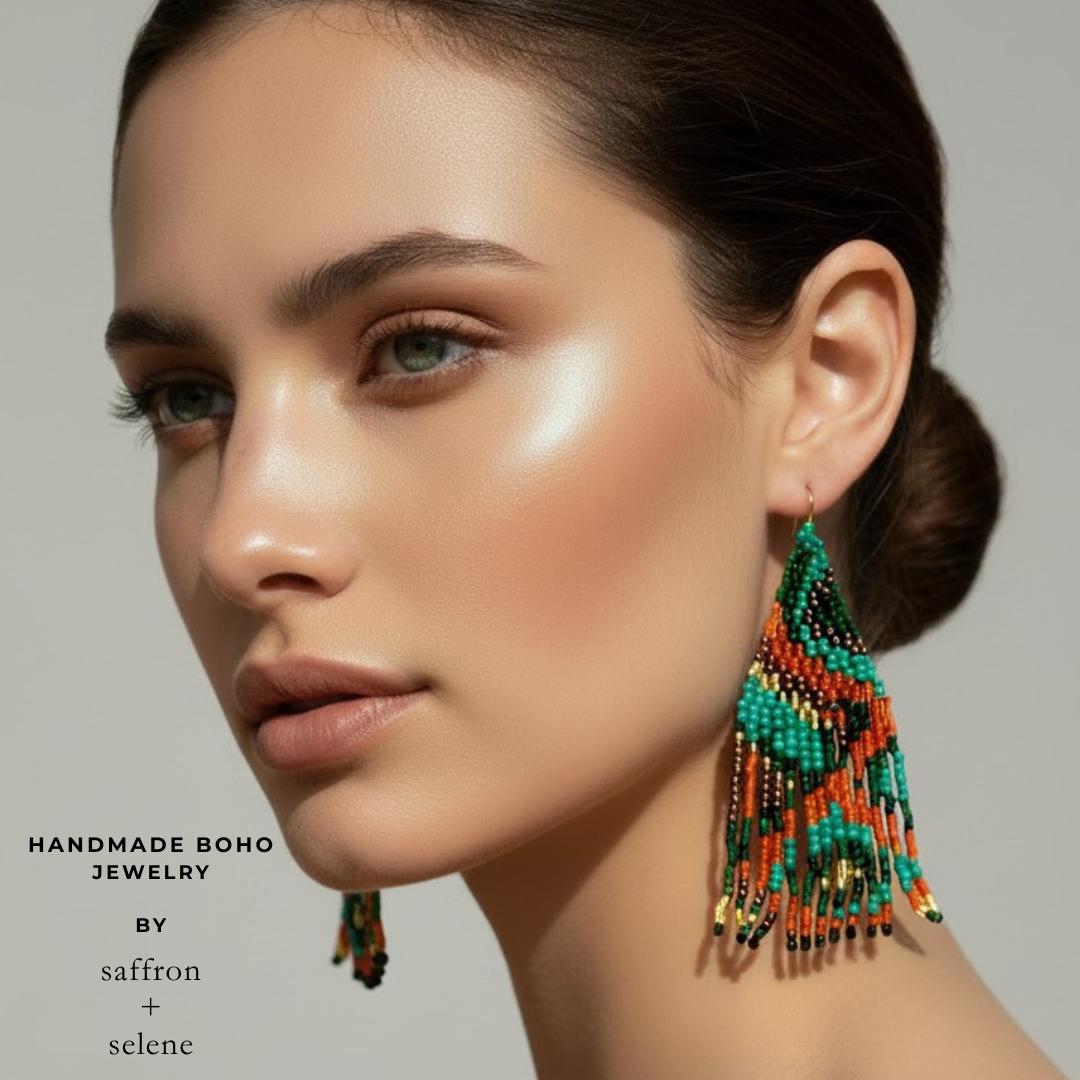 Long statement earrings with forest green and burnt orange beadwork creating dramatic movement