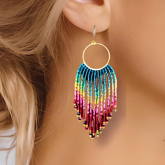 Handmade multi coloured fringe earrings.  Ombre rainbow coloured hand beaded tassels with metalic gold highlights, hanging from a 9kt gold plated circular hoop.  Hand threaded by Saffron and Selene Boho Jewelry for Women