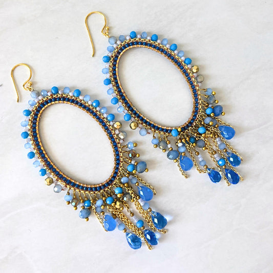 Handmade blue statement earrings with gold oval frame and faceted crystal drops.